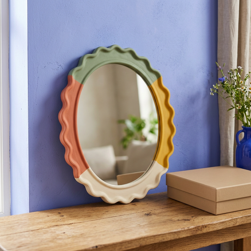 Four-color scalloped oval decorative mirror beside a plain beige box on an oak console