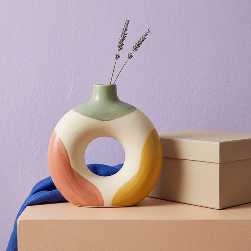 Color-block ring vase styled with two dried stems against a lavender wall